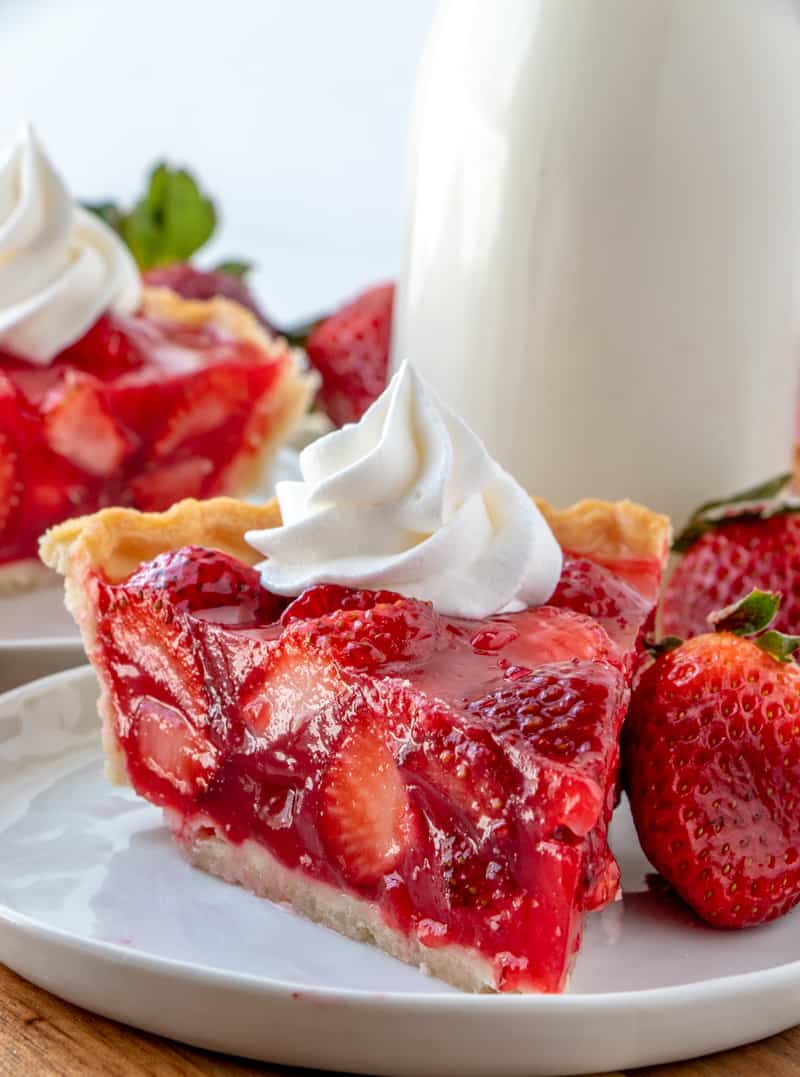 Easy delicious and bursting with flavor this Strawberry Pie is an old-fashioned recipe that has minimal ingredients intense strawberry flavor and absolutely addicting. Close up photo of side of strawberry pie with whipped cream